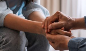 two sitting people holding hands